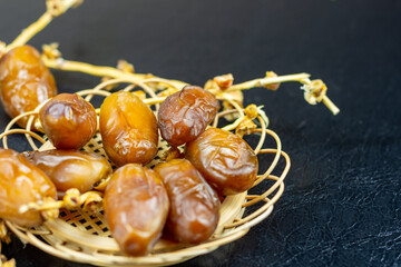 Close-up of Algerian royal dates on a wooden plate on a black background. Ramadan concept.