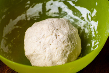Dough ball in plastic bowl. Preparation of yeast dough for making bread, pizza bases.