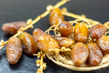 Close-up of Algerian royal dates on a wooden plate on a black background. Ramadan concept.