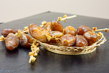 Close-up of Algerian royal dates on a wooden plate on a black background. Ramadan concept.