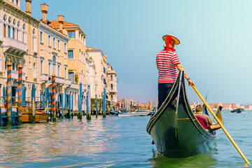 A Venetian gondolier leisurely rows past the historic buildings in the rio grande. - obrazy, fototapety, plakaty