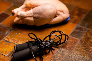 Raw chicken carcass and jump rope on stone background. Sports nutrition, diet concept.