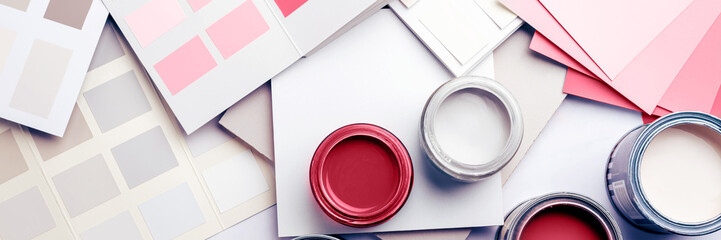 Tiny sample paint cans during house renovation, process of choosing paint for the walls, different green and beige colors, color charts on background
