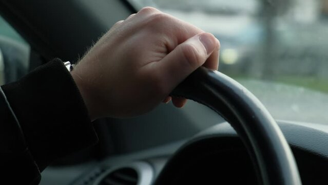 The driver's hand on the steering wheel of the car while driving, closeup.