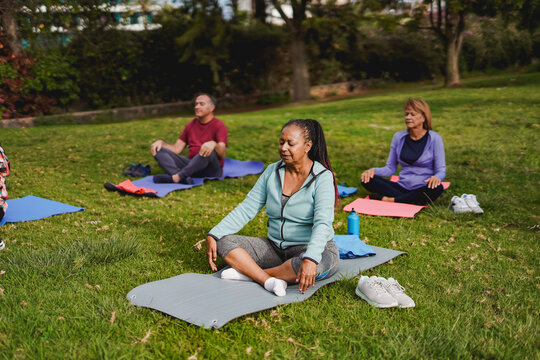 Multiracial senior people doing yoga meditation at city park - Focus at african woman - Powered by Adobe