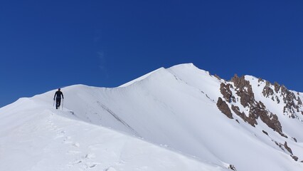 Rear view of a man with hiking poles on snowy mountain peak. Erciyes Mountain, Turkey