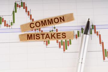 On the chart of business quotes lies a pen and torn paper with the inscription - Common Mistakes