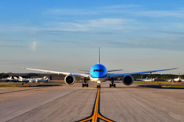 A jumbo jet airplane taxing on the runway preparing to take off with the airport in the background