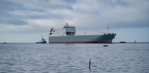 naval tug accompanying a cargo ship to the port entrance
