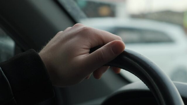 The driver's hand on the steering wheel of the car while driving, closeup. Driving concept
