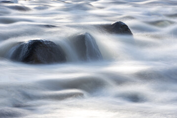 Flowing Blurry River Water Because of the Long Exposure. Background. Stones in background.