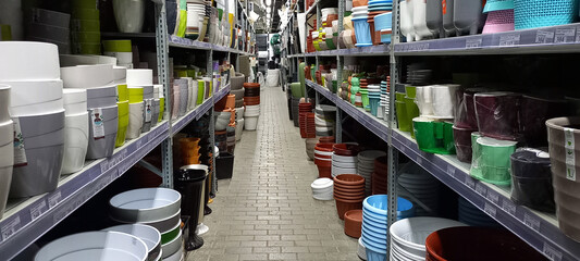 Empty flower pots in a store or greenhouse. Ceramic or plastic flower pots at the shop. Colorful flower pots on the shelf in the store. Colorful pots for plants.