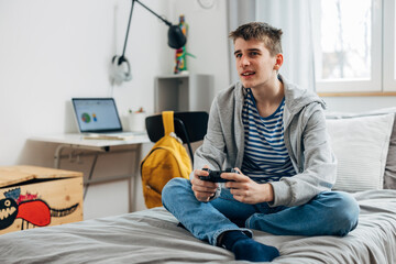 Adolescent boy is alone in his room playing video games