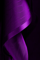 Abstract background. Swirling roll of  pink purple satin fabric.Selective focus.