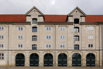 Front exterior view of typical old brick building with wooden arch gate entrance for garage along waterside of Copenhagen, Denmark. 