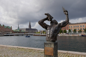 Selective focus at Freedom statue by Bright Bimpong and background of Børsen, waterfront building with a striking spire and Christiansborg Palace in Copenhagen, Denmark. 