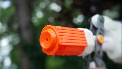 Water gun spraying water close up outside. Plastic Toy Weapon splashing water in slow motion. Water blaster game concept