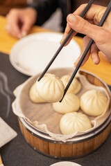 Fototapeta na wymiar hand with chopsticks taking delicious dumpling from traditional bowl, healthy food ready to eat in restaurant, asian tradition