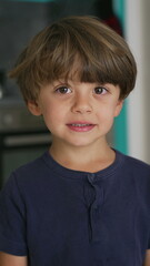 Portrait of a handsome small boy looking at camera smiling. Close up face of child in Vertical Video