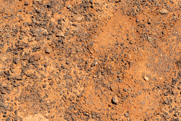 Fondo textura de tierra volcánica seca y desértica en tonos dorados y ocres con el sol brillando. piedras y arena de fuerteventura.