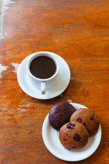 Sturdy Americano in a white cup and three chocolate chip cookies top view on a wooden background