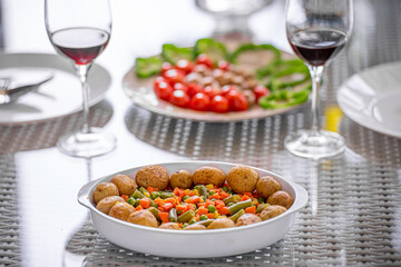 Dining table with potato dish ,salad and wine