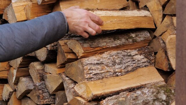 A man picks up firewood for heating from a woodpile.