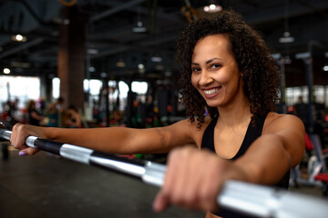 Sexy gorgeous african american woman training with barbell at the gym