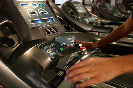 I am ready to workout Close up photo of woman hand pushing a start button on treadmill at gym. Cardio workout