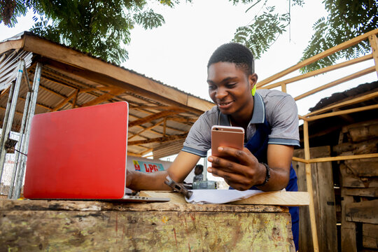 young african carpenter standing holding working calling laptop