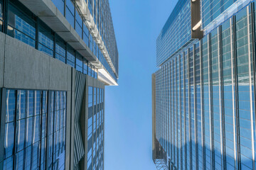 Austin, Texas- Low angle view of modern buildings with glass exterior against the blue sky. There are two buildings on both sides and a clear blue sky in the middle background. - Powered by Adobe