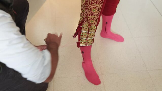 Assistant bullfighter or banderillero helping to dress tying ropes on the pants of the lights suit