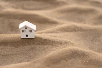 Close-up of a model of a wooden house on a sandy wave
