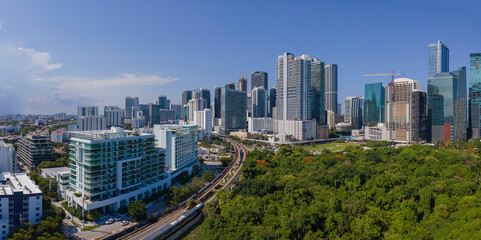 Aerial view of urban landscape with modern city skyline in Miami Florida. Buildings, residences, road, and foliage can be seen against the blue sky on this sunny day.