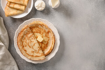 Russian thin pancakes or blini with butter on gray stone background. Top view. Classic recipe. Copy space.