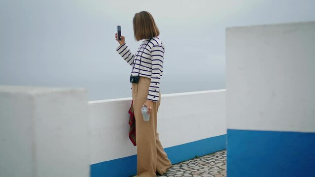 Tourist making vacation pictures at seaside. Beautiful blogger creating content