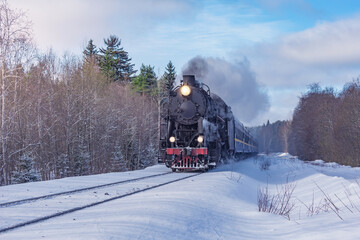 Retro steam train moves at winter day.