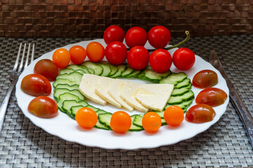 A plate of cherry tomatoes, cucumbers and cheese