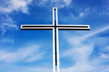 Big metal christian cross high in the blue sky. Symbol of love for Jesus. Catholic church monumental construction. Crucified jesus christ. Outdoor pray.