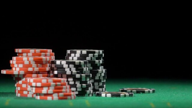 Throws black chip, slow motion. Red and black chip stacks on green gaming table.