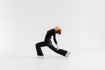Young Girl, professional hip-hop dancer in a black clothes performing over a Isolated white background with a plenty of copy space.