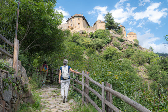 Women hicking by Juval Castle (German: Schloss Juval, Italian: Castel Juval) is a medieval castle located in Vinschgau in Kastelbell-Tschars in South Tyrol - Trentino Alto Adige S&uuml;dtirol.