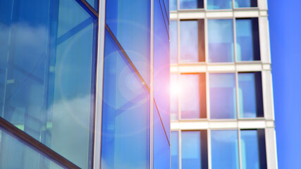 Looking up at the commercial buildings in downtown. Modern office building against blue sky. Windows of a modern glass building.