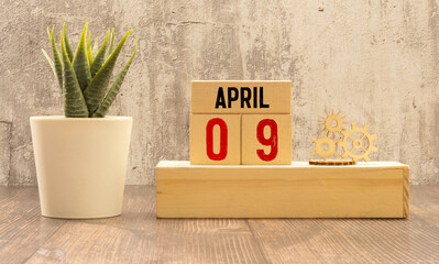 April 9 calendar date text on wooden blocks with blurred park background. Copy space and calendar...