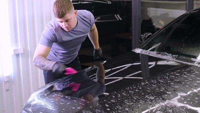 Man covering car with vinyl polyurethane tape. Films for the car. Sticker protective film on the car