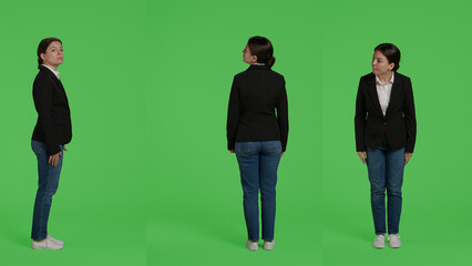Obraz premium Female corporate model wearing formal suit standing over full body greenscreen backdrop, being casual and relaxed in studio. Company employee waiting on green screen background.