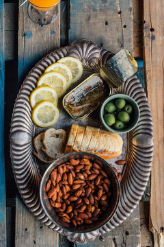 high angle view of tinned fish sardines snack platter silver tray with almonds, bread, green olives, lemon slices