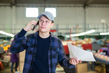 Worker conducts business negotiations on the phone in a factory floor on fruit processing plant.