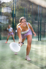 Active womans with enthusiasm playing padel on the tennis court