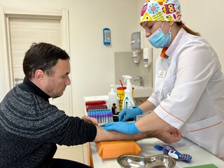 Hand of nurse, doctor or Medical technologist in blue gloves taking blood sample from a patient in...
